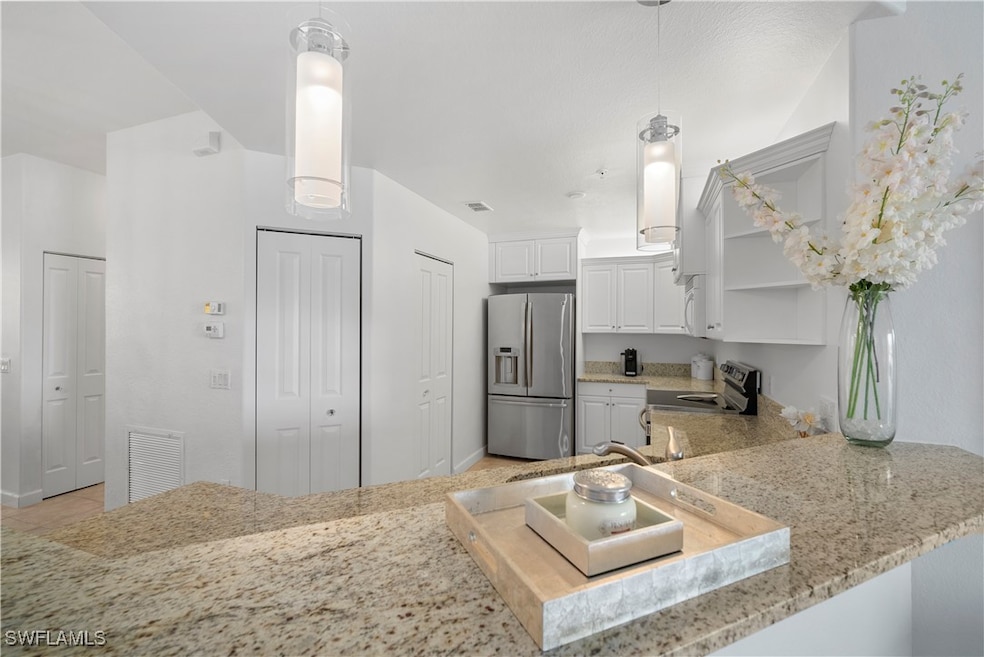 Kitchen with white cabinetry, decorative light fix