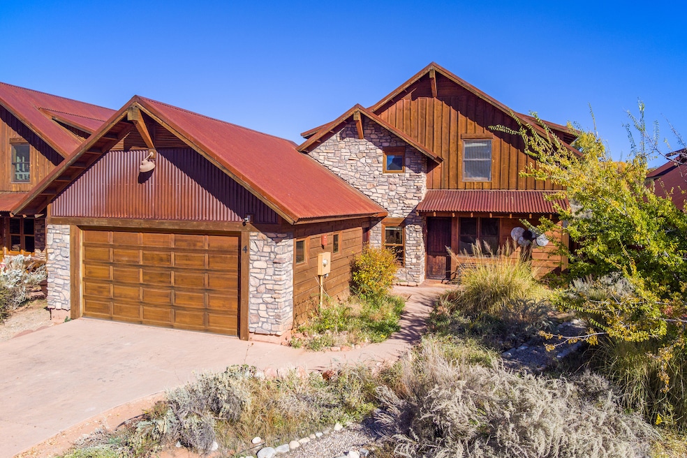 View of front of property with stone siding, an attached garage, driveway, and a porch