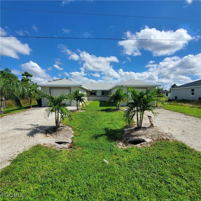 View of front of home with dirt driveway, a front lawn, a garage, and stucco siding