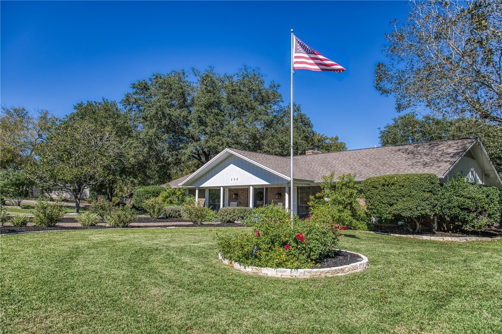 View of front of house featuring a front lawn, covered porch, brick siding, and a chimney
