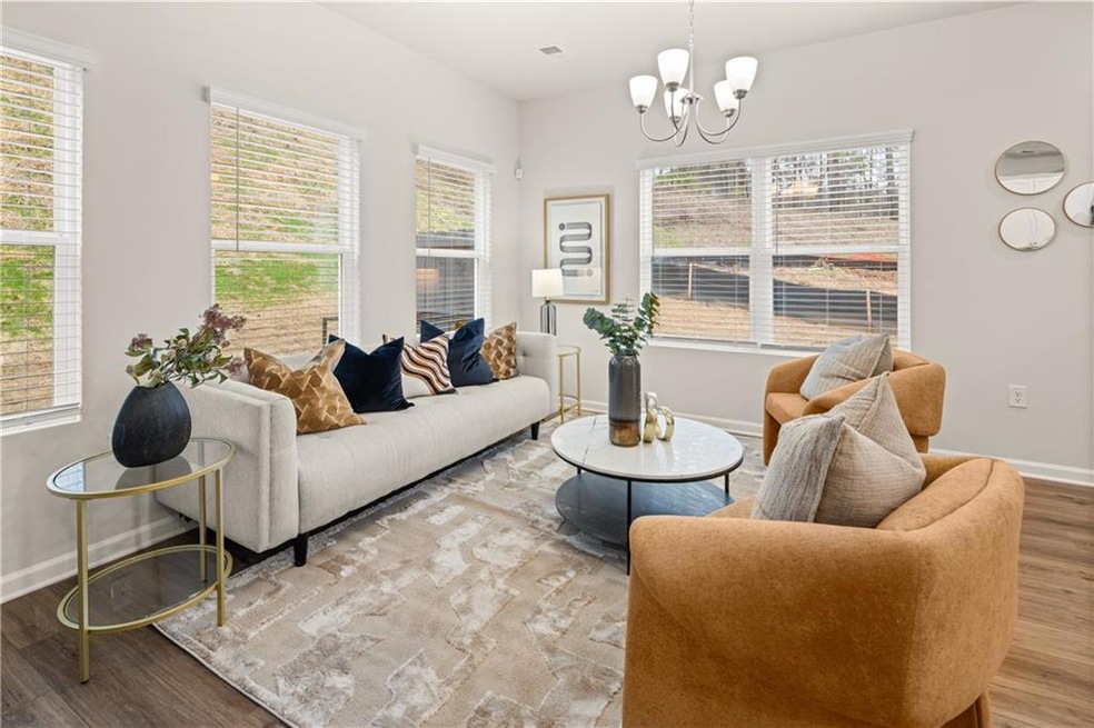 Living room with wood finished floors, a chandelier, and baseboards