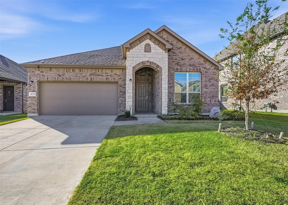 French provincial home featuring a front lawn, brick siding, concrete driveway, an attached garage, and roof with shingles
