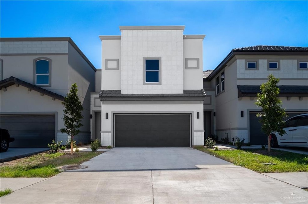 View of front of property featuring stucco siding, concrete driveway, and an attached garage