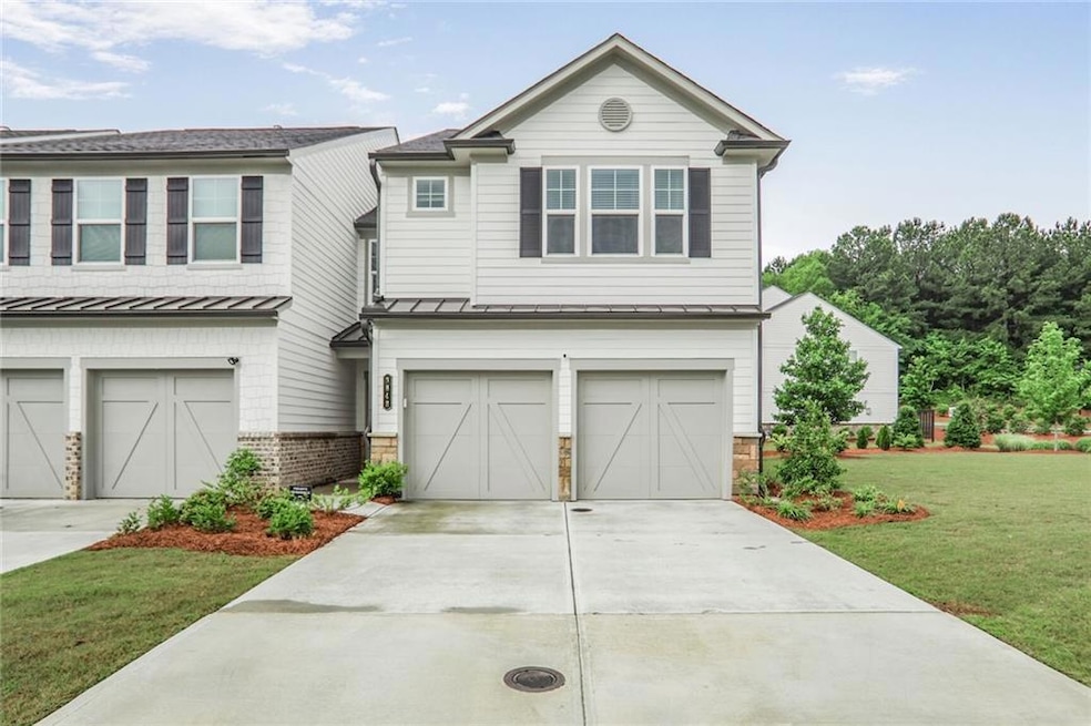 View of front of home featuring a 2-car garage, a standing seam roof, a side lawn, and driveway