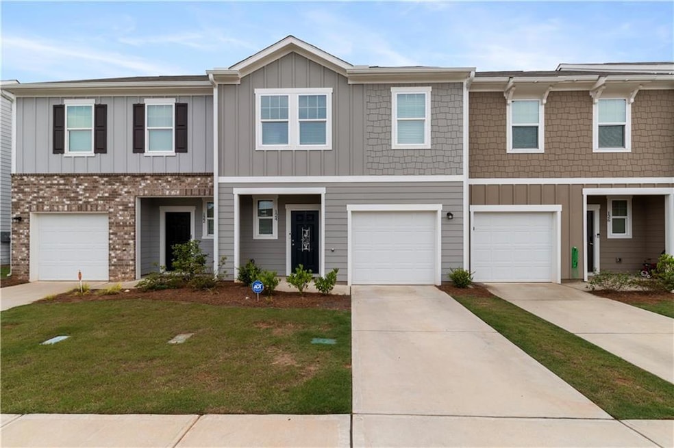 Townhome / multi-family property featuring board and batten siding, a front lawn, an attached garage, and driveway