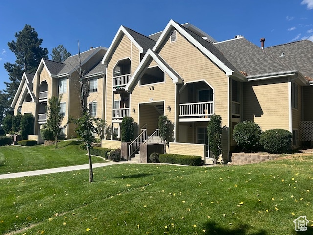 View of front of house featuring a balcony and a front yard