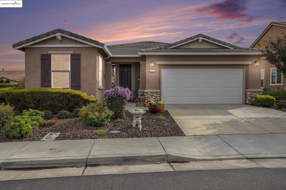Ranch-style house with stone siding, a tiled roof, stucco siding, driveway, and an attached garage