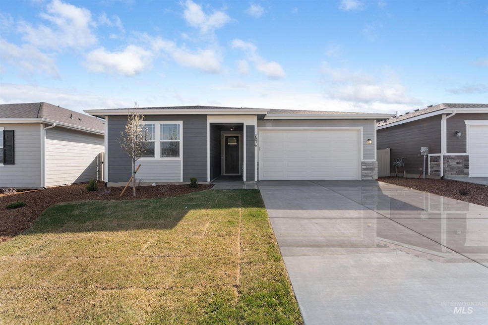 View of front of home featuring driveway, a front yard, and a garage