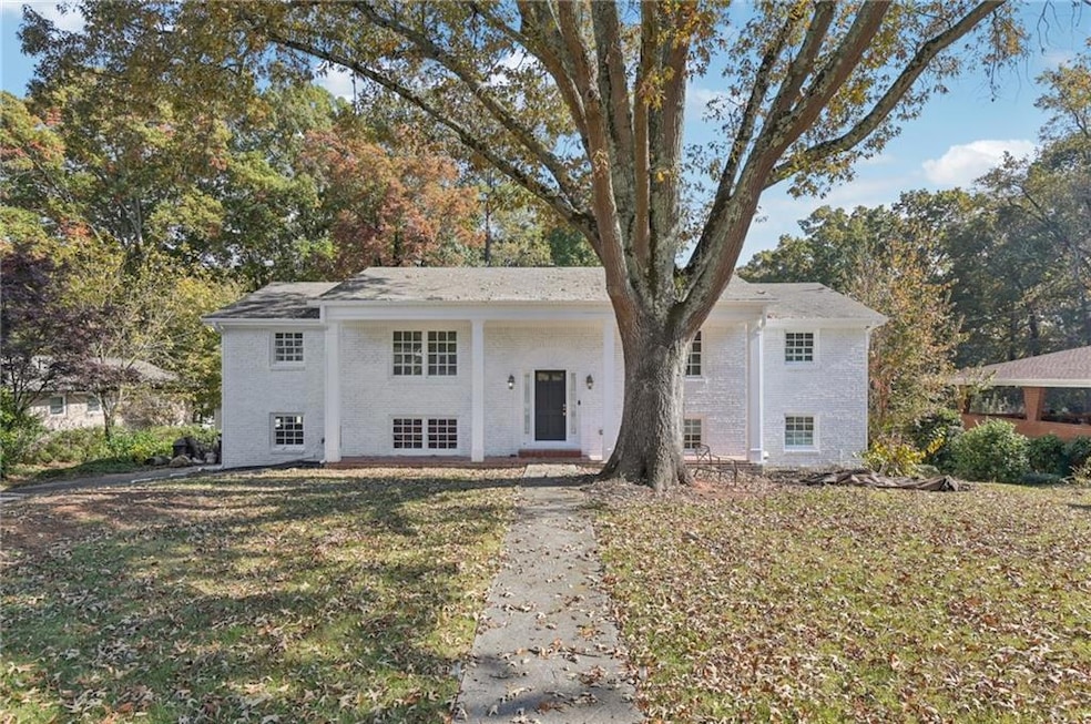 Raised ranch featuring a porch, brick siding, and a front yard