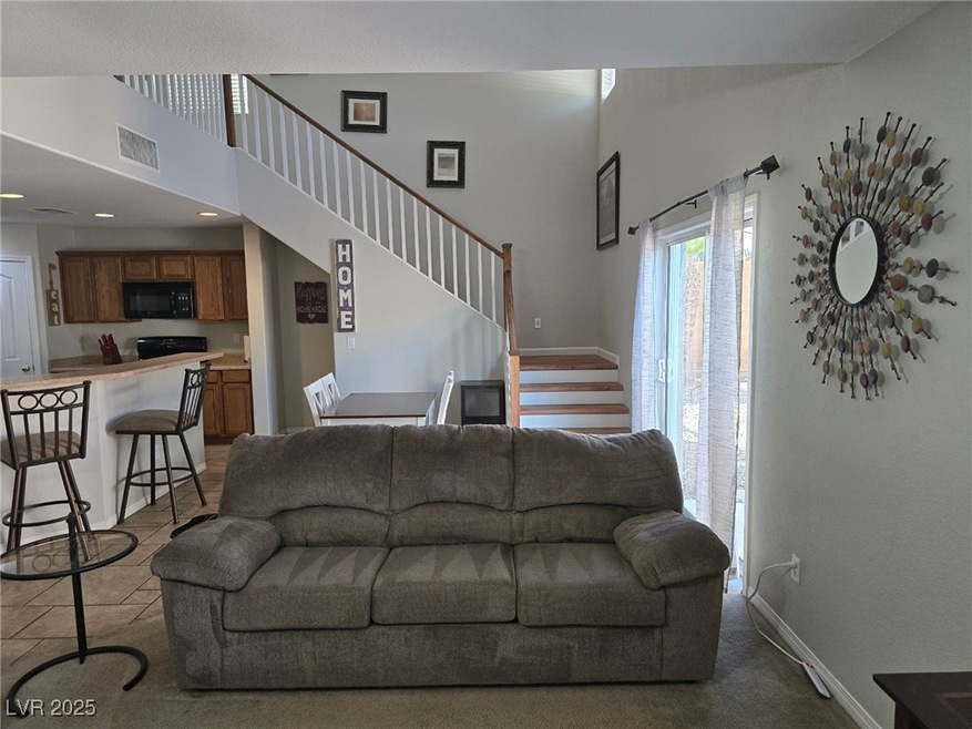Living room with stairway, a high ceiling, and bas