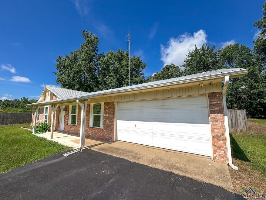 View of front facade with brick siding, an attached garage, driveway, and a metal roof