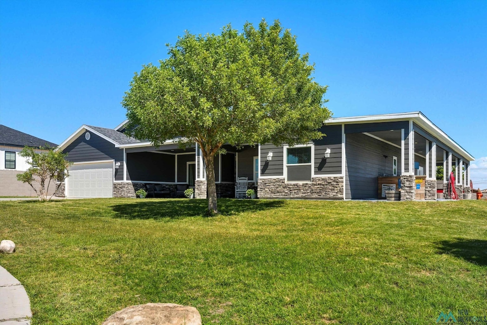 View of front facade with stone siding, a front yard, and a garage