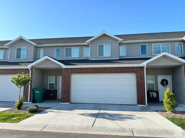 Traditional home featuring a garage, brick siding, concrete driveway, and a shingled roof
