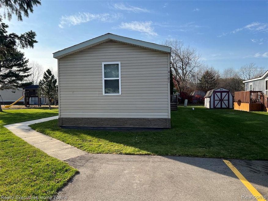 View of side of property with a lawn, a shed, and a playground