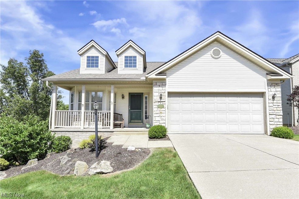 View of front of property with garage, a porch, and a front lawn