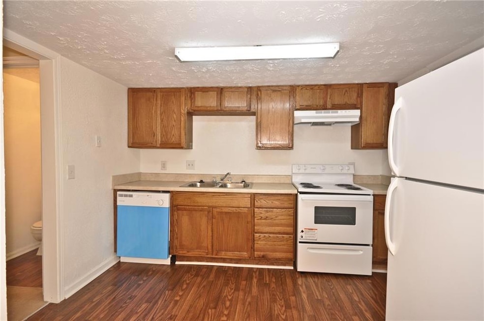 Kitchen with sink, a textured ceiling, white appli