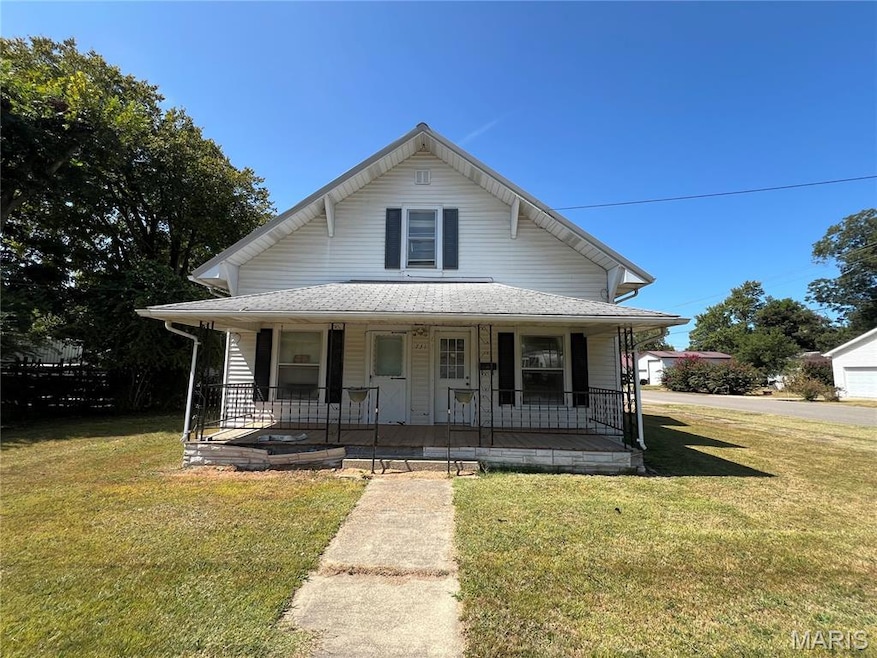 View of front of house with a porch, a front yard, and roof with shingles