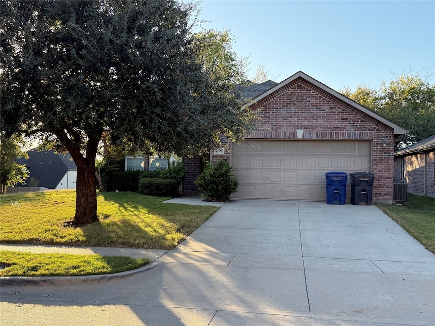 View of front facade featuring brick siding, a front yard, driveway, and a garage