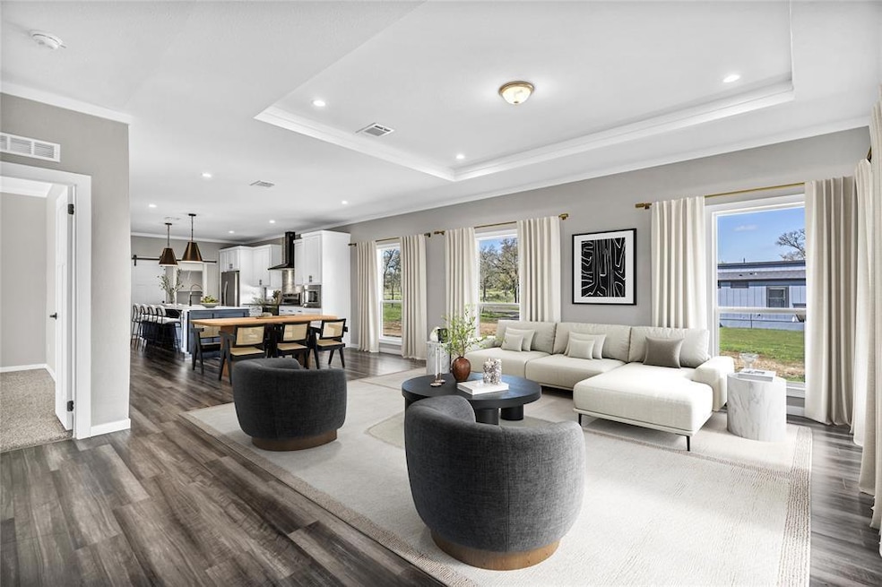 Living room featuring a tray ceiling, crown molding, dark wood-type flooring, and recessed lighting