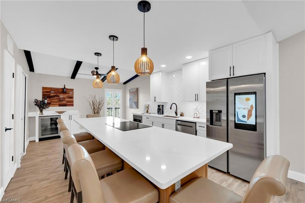 Kitchen with white cabinetry, appliances with stainless steel finishes, a breakfast bar area, beamed ceiling, and light wood finished floors