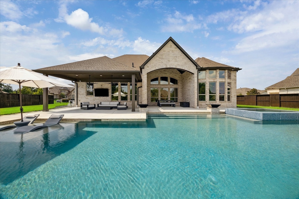 The rear elevation of this magnificent home is as architecturally pleasing as the front. The ultimate private oasis. Entertain outdoors beneath the 25'x13' covered living area!