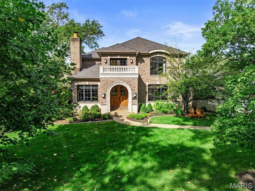 French country home with a balcony, a front lawn, brick siding, a chimney, and a shingled roof