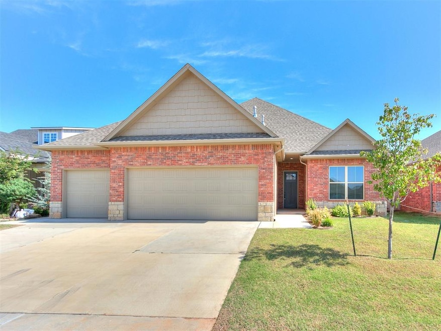 View of front of property featuring an attached garage, a front lawn, a shingled roof, concrete driveway, and brick siding