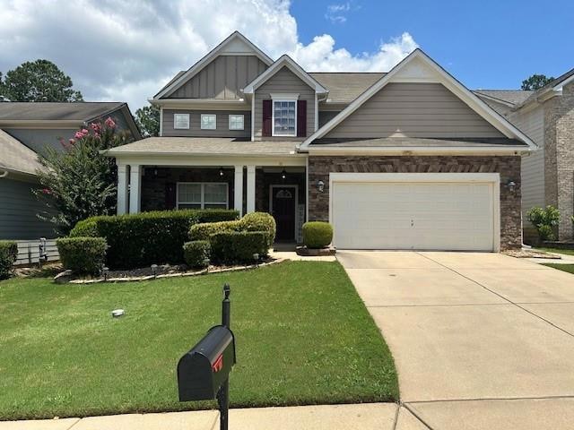 Craftsman-style home featuring a front yard, driveway, a garage, and board and batten siding