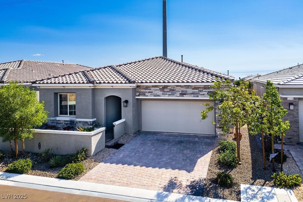 View of front of property featuring stone siding, a tiled roof, decorative driveway, and stucco siding