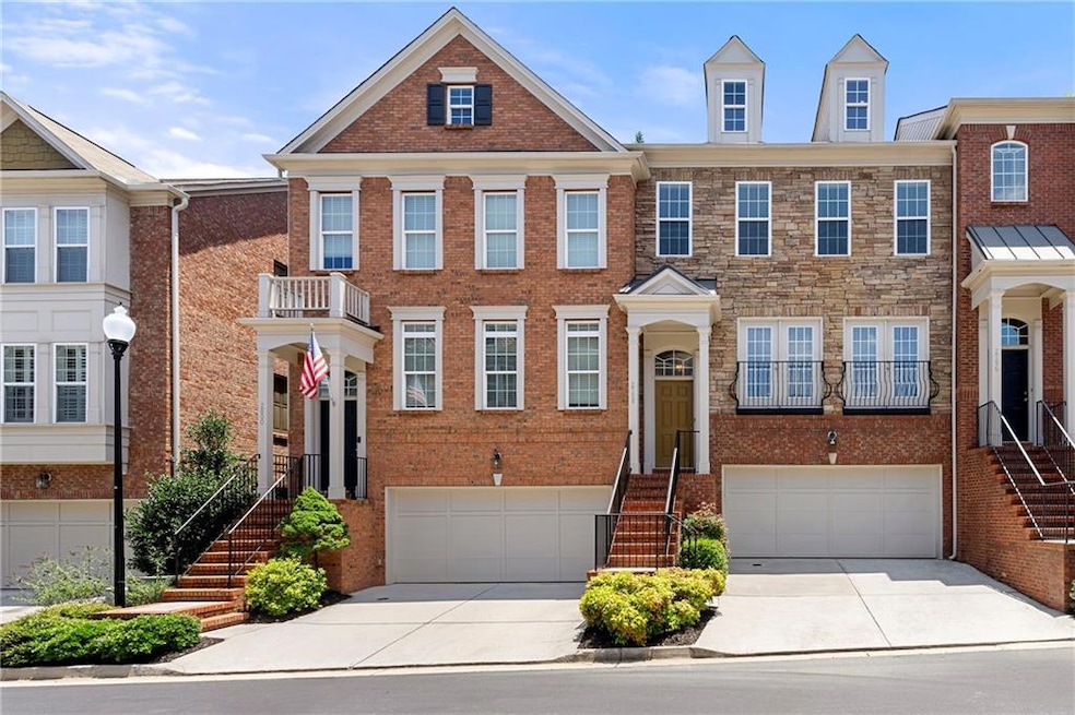 Multi unit property featuring stairs, driveway, an attached garage, and brick siding