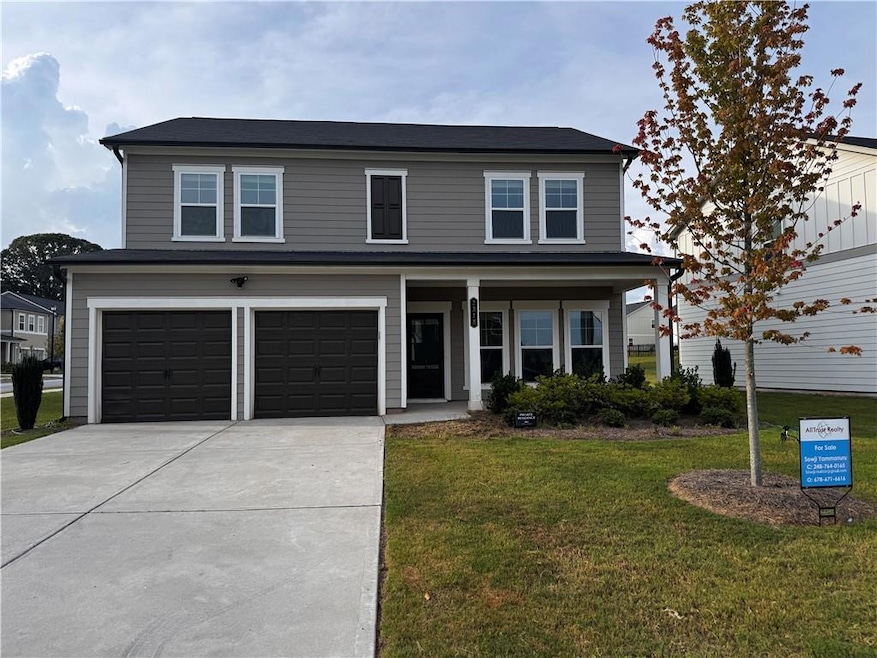 View of front facade featuring an attached garage, a front lawn, driveway, and a porch