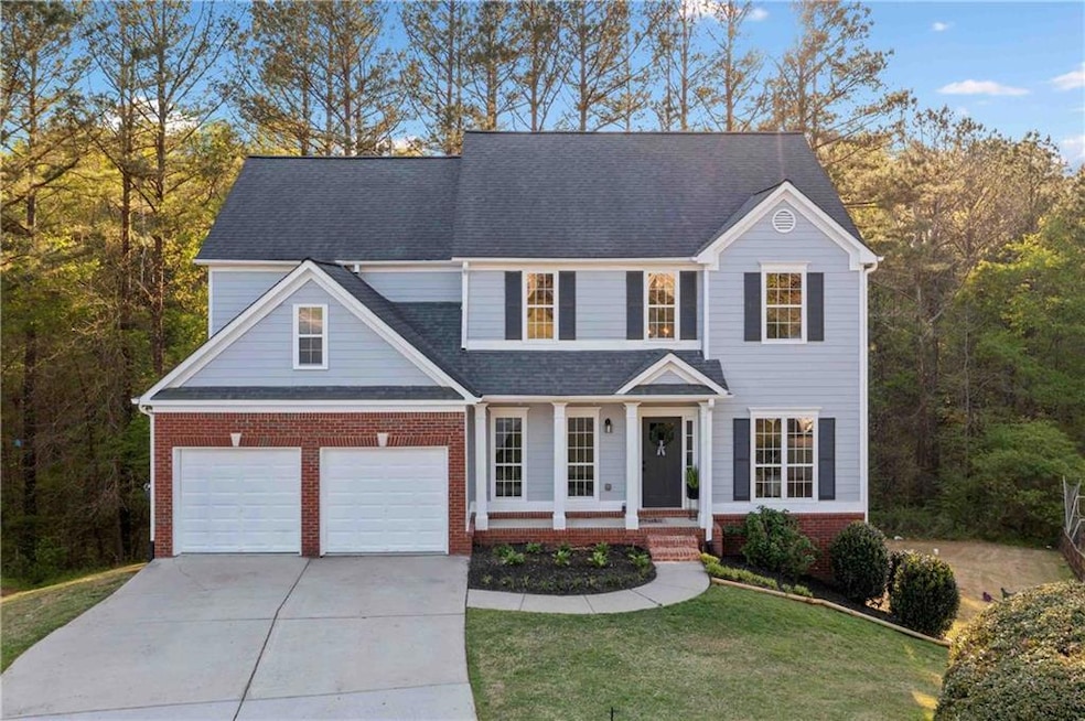 Traditional-style home with covered porch, concrete driveway, brick siding, a front lawn, and roof with shingles