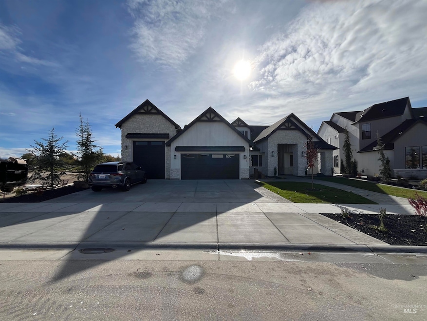 View of front of property featuring stone siding, concrete driveway, and an attached garage