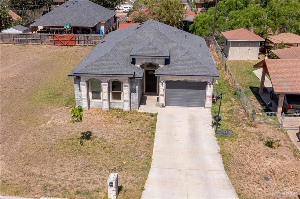 French country inspired facade featuring concrete driveway, fence, an attached garage, brick siding, and a shingled roof