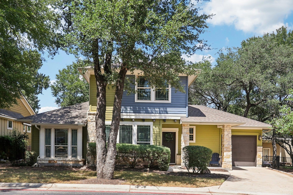 View of front facade featuring roof with shingles, stone siding, an attached garage, and driveway