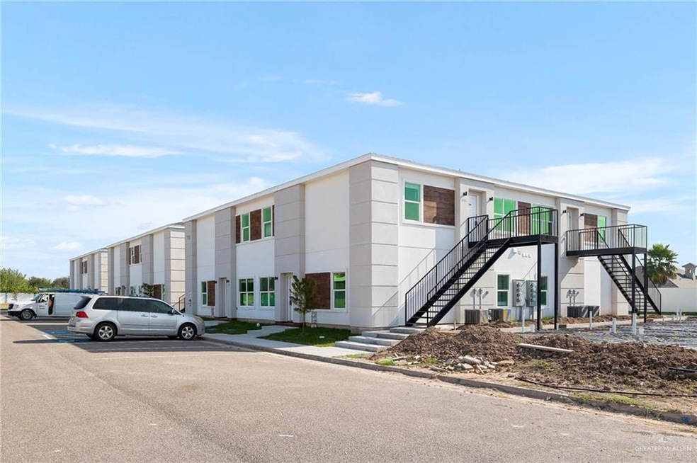 View of building exterior with stairway and uncovered parking