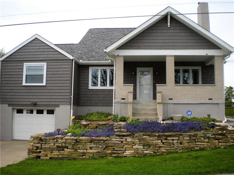 Front with large porch and stone wall.