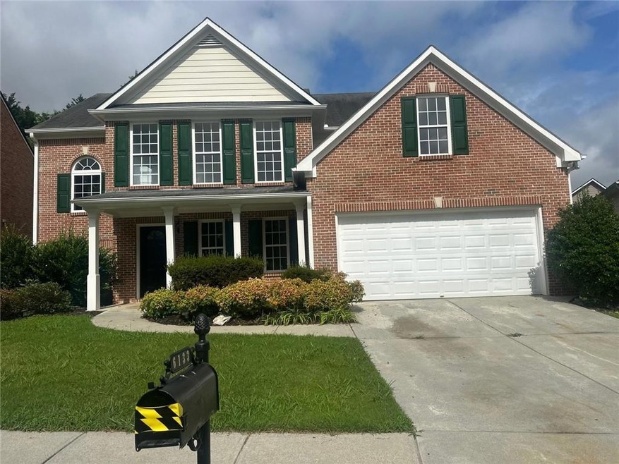 Traditional-style house with a front lawn, driveway, brick siding, and a porch