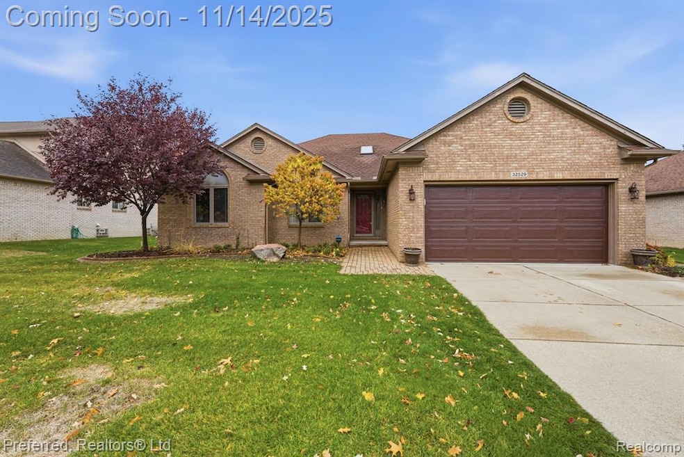 Ranch-style house featuring brick siding, concrete driveway, a front yard, and an attached garage