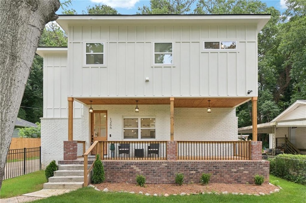 View of front of house with brick siding, covered porch, and board and batten siding