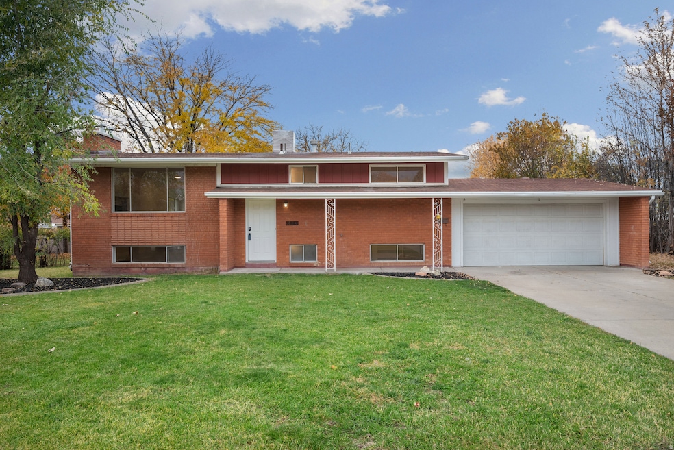 View of front facade featuring a front yard, driveway, brick siding, and an attached garage