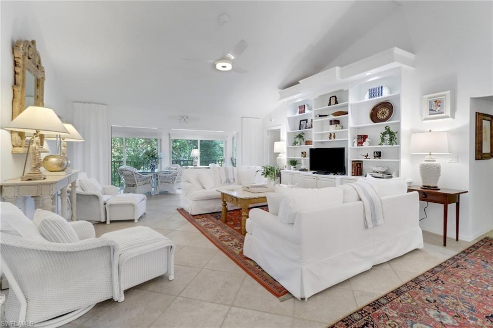 Tiled living room with ceiling fan and vaulted cei