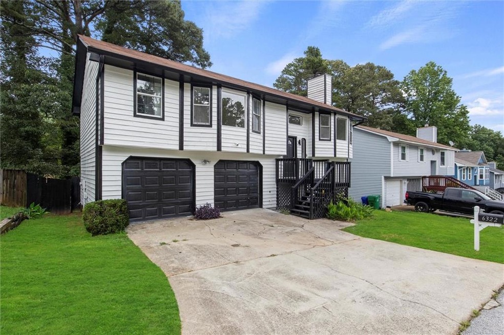 Split foyer home with a chimney, an attached garage, a front lawn, and driveway