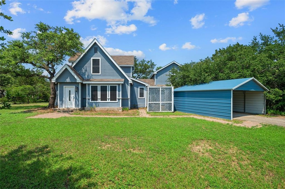 Rear view of house with a carport, dirt driveway,
