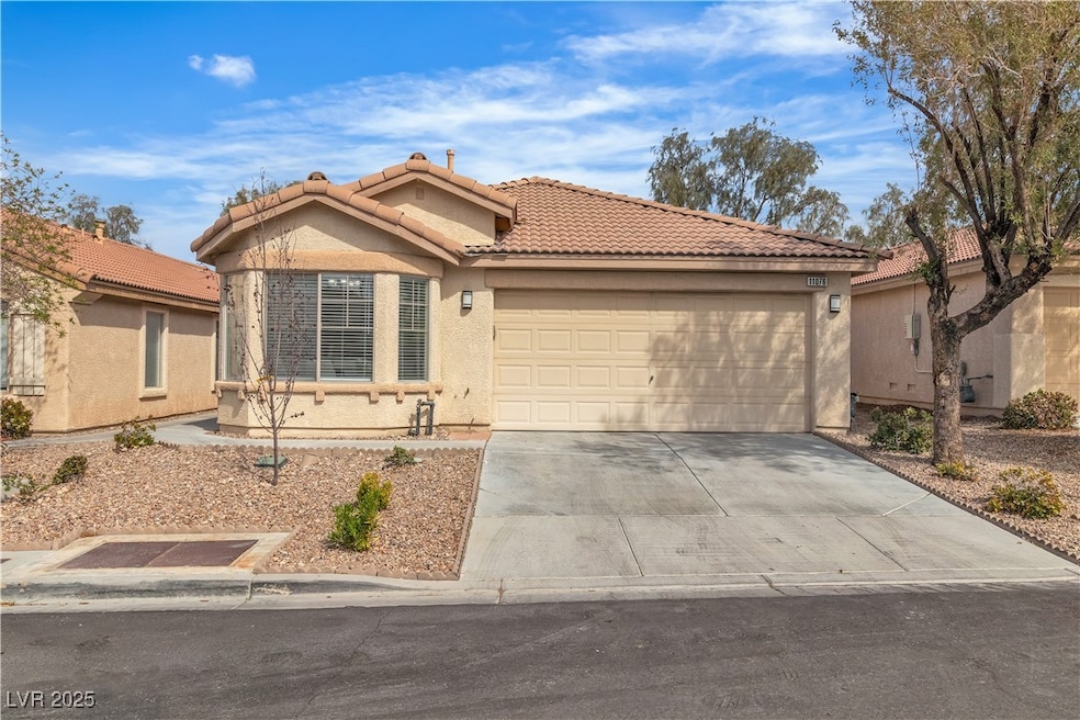 View of front facade with stucco siding, concrete driveway, a garage, and a tile roof