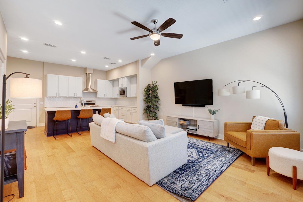 Living area with ceiling fan, light wood-style fl