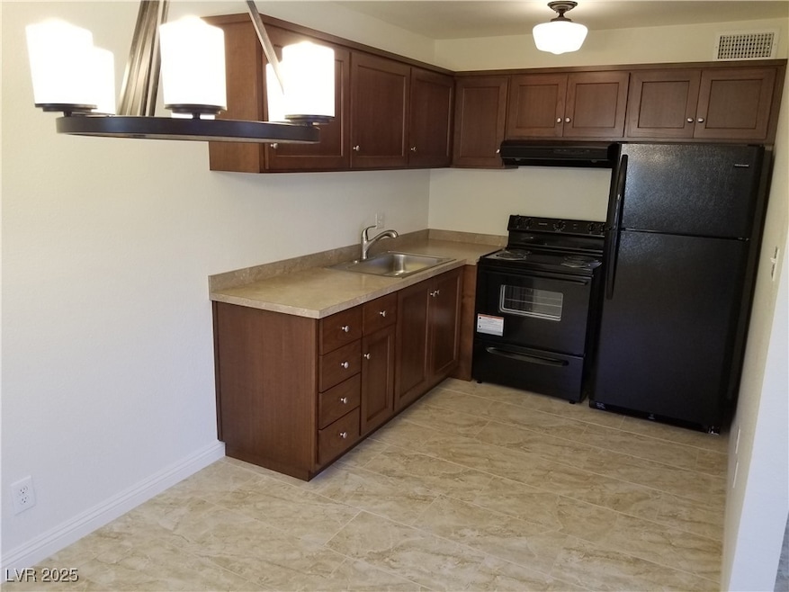 Kitchen featuring visible vents, a sink, light countertops, black appliances, and extractor fan