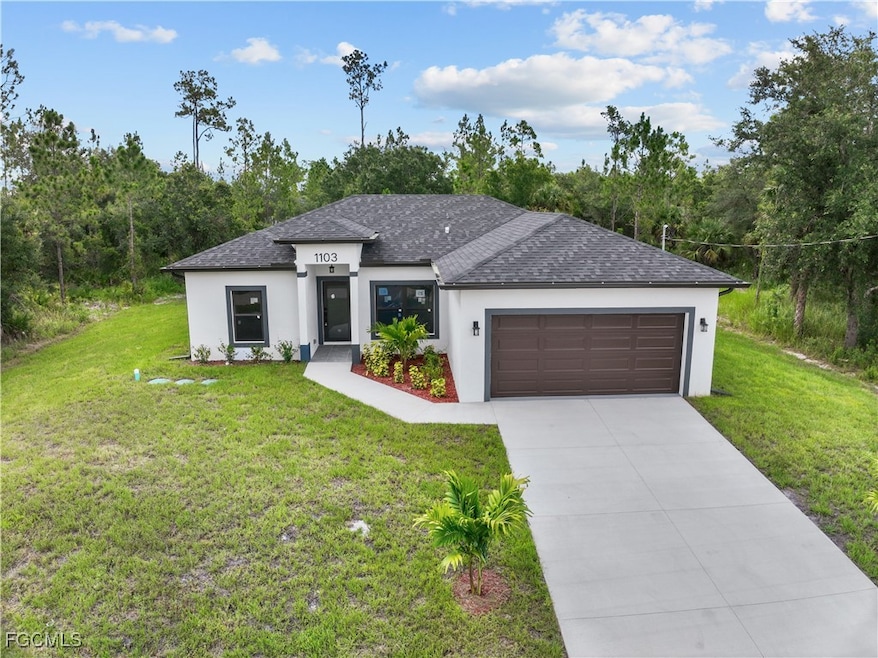 Prairie-style home featuring stucco siding, a garage, a front yard, and roof with shingles
