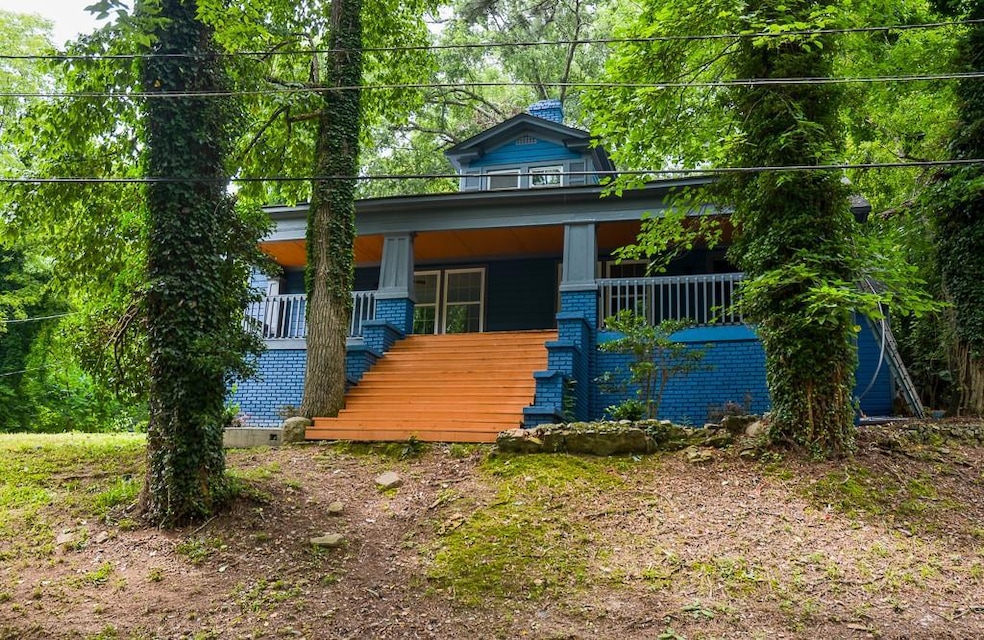 View of front of home featuring stairway, a porch, brick siding, and a chimney
