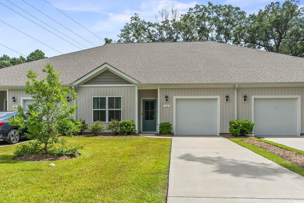 View of front of property featuring a shingled roof, a front yard, driveway, a garage, and board and batten siding